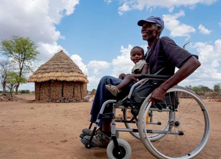 Man sits in wheelchair with smiling baby on his knee