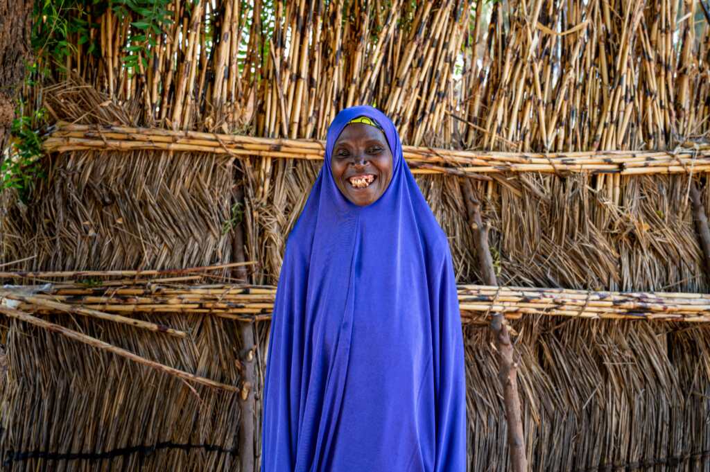 A woman from Nigeria smiling. She is wearing a blue abaya.