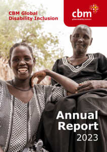 The cover photo for the CBM Global Disability Inclusion Annual Report 2023 features two women from Kenya in a natural setting, sharing a joyful moment. The younger woman, dressed in a patterned black and white dress, smiles broadly. The older woman, wearing a simple black dress with white embroidery, looks on with a gentle smile. Both are seated outdoors. The CBM Global logo is visible at the top, with the words "Annual Report 2023" prominently displayed at the bottom.