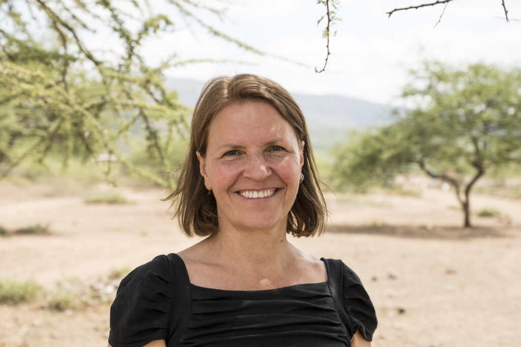 Kirsty Smith, Chief Executive of CBM UK, smiling outdoors in a rural setting with trees and hills in the background.