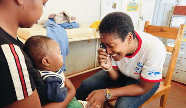 A healthcare worker in Madagascar uses a small Arclight device to examine a baby’s eyes while the mother holds the child during an early eye screening session at a community health centre.