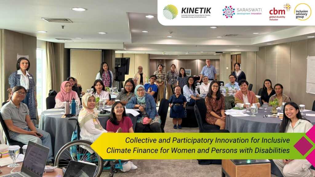 A large group of workshop participants gather for a group photo in a conference room, seated and standing around round tables. At the top of the image are logos of KINETIK, Saraswati, CBM Global Disability Inclusion Inclusion Advisory Group. A banner at the bottom reads “Collective and Participatory Innovation for Inclusive Climate Finance for Women and Persons with Disabilities.”